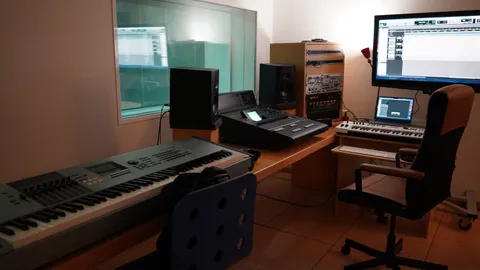 Studio desk with monitors, a synthesizer keyboard and an office chair