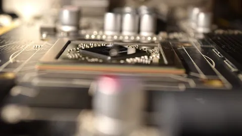 Close-up of a graphics processor chip on a graphics card circuit board, surrounded by small components and capacitors
