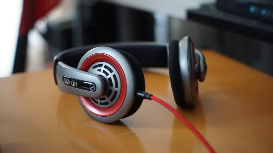 Over-ear headphones with a red cable resting on a wooden desk