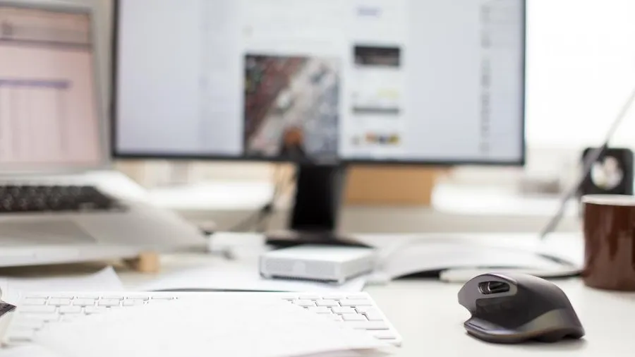 Computer mouse on a desk in front of a monitor