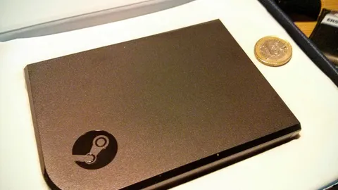 Valve's original Steam Link streaming box, a small black square with the Steam logo, in its packaging next to a one-euro coin