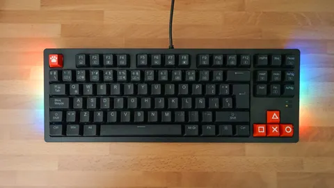 Tenkeyless mechanical keyboard with red accent keycaps and RGB underglow on a wooden desk